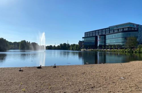 a fountain in the middle of a lake with a building at Genting Hotel & Spa at Resorts World Birmingham in Bickenhill
