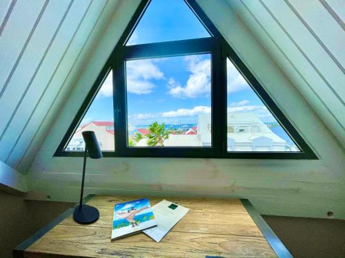 a window in a room with a desk with a book and a lamp at Centr'Hotel in Marigot