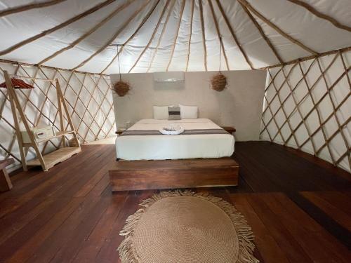 a bedroom in a yurt with a bed and a rug at Huaya Camp in Tulum