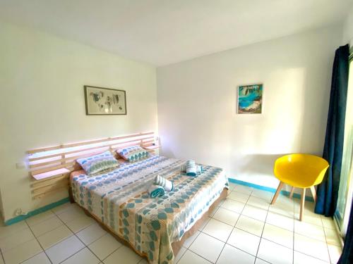 een slaapkamer met een bed en een gele stoel bij Studio Carayou & Spa in Les Trois-Îlets