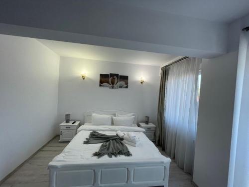 um quarto branco com uma cama e duas mesas de cabeceira em Deny's Apartament em Gura Humorului