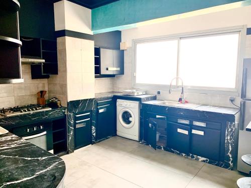 a kitchen with blue cabinets and a washing machine at Anfa 118 - Best view in town - 3 bedrooms - 2 Bathrooms in Casablanca