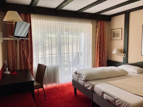 Schlafzimmer mit einem Bett, einem Schreibtisch und einem Fenster in der Unterkunft Berg-Gasthof Hötzelein in Kunreuth