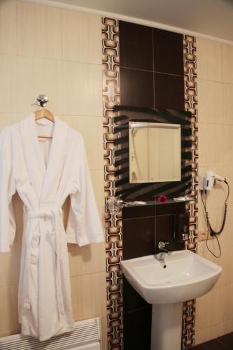 a white robe hanging on a rack next to a sink at Evropeyskiy in Kyiv
