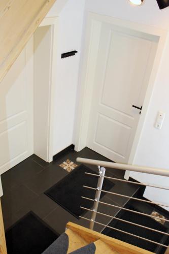 a staircase with white doors and a black floor at Ferienhaus Traumblick direkt am See in Weißenstadt