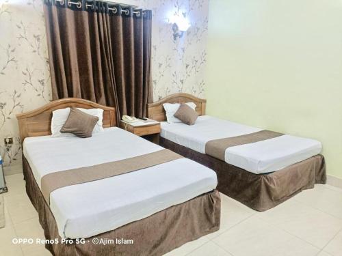 dos camas sentadas una al lado de la otra en una habitación en Hotel Royal Avenue, en Chittagong