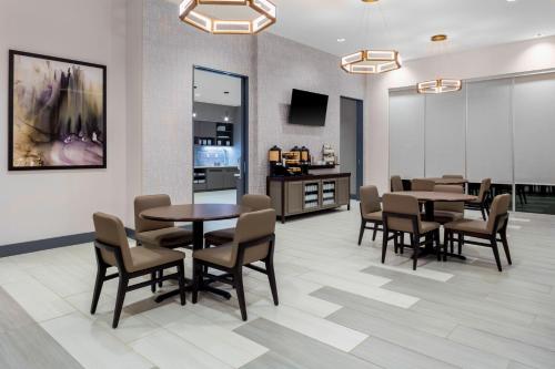 a dining room with tables and chairs and a kitchen at Hyatt House Charlotte Rea Farms in Charlotte