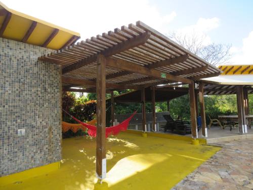 a covered patio with a red hammock under a wooden pergola at Casa de Campo Junto al Mar en San Andrés in El Cove