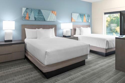 two beds in a hotel room with two lamps at Hyatt House Charlotte Rea Farms in Charlotte