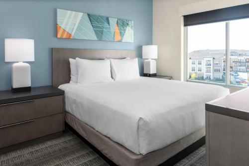 a bedroom with a large bed and a large window at Hyatt House Charlotte Rea Farms in Charlotte