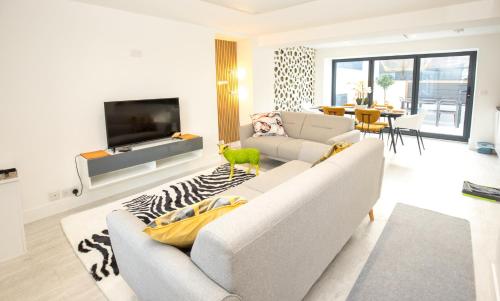 a white living room with a couch and a tv at James' Place at Castle Cottage in Merthyr Tydfil