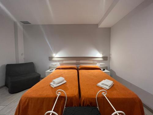 een slaapkamer met een bed met oranje lakens en een stoel bij Apartamentos Comfort Calella in Calella