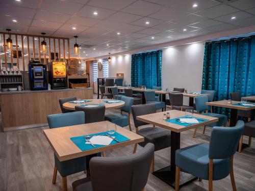 une salle à manger avec des tables et des chaises bleues dans l'établissement Contact Hotel Restaurant Bleu France - Eragny Cergy, à Éragny