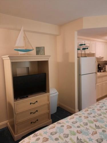 a bedroom with a bed with a television and a refrigerator at A Happy Seashell Story in Daytona Beach