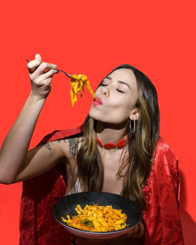 a woman is eating food with a bowl of food at Lush Motel Ipiranga in Sao Paulo