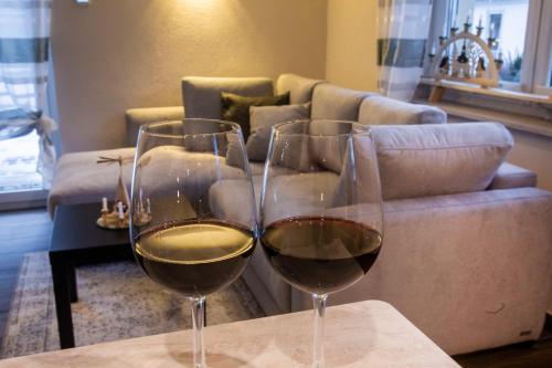 - deux verres de vin assis sur une table devant un canapé dans l'établissement Ferienwohnung Rotbuche, à Tannenberg