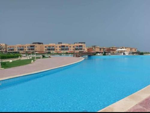 een groot blauw zwembad met gebouwen op de achtergrond bij Blumar Eldome Sea Virw in Ain Sokhna