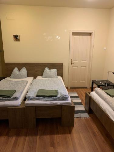 two beds in a room with wooden floors and a door at Ica Vendégház in Süttő
