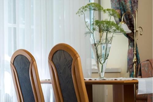 a table with a vase on top of it with chairs at Apartma Vila Golf in Rogaška Slatina
