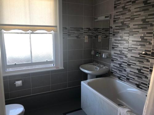a bathroom with a tub and a sink and a toilet at BEST WESTERN New Holmwood Hotel in Cowes