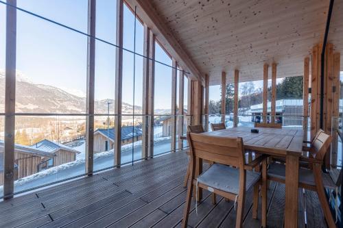 a dining room with a table and chairs and windows at Bergresort Hauser Kaibling by ALPS RESORTS in Haus im Ennstal