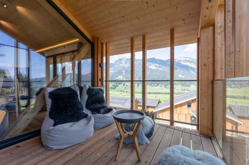 a room with couches and pillows on a balcony with mountains at Bergresort Hauser Kaibling by ALPS RESORTS in Haus im Ennstal