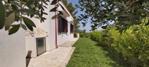 a white building with a walkway next to a yard at Villa del Sole in Manduria