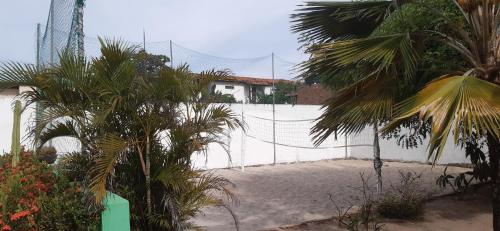 a white fence with palm trees in front of a house at Casa de Praia - Francês/Marechal Deodoro in Marechal Deodoro