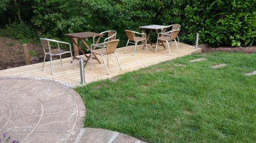 una terraza de madera con sillas y mesas en un patio en Riverwood Retreat - Self Contained Lux Apartment 
