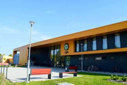 a building with a red bench in front of it at Sport Centrum Apartman in Pápa