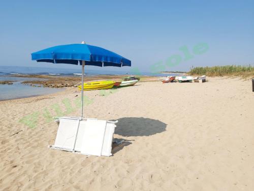 a chair and an umbrella on a beach at Villa del Sole in Manduria