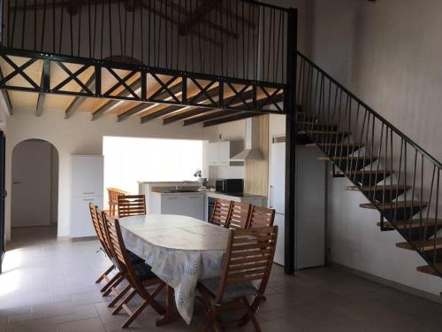 une salle à manger avec une table, des chaises et un escalier dans l'établissement Maison au Vieil à NOIRMOUTIER, à Le Grand Vieil