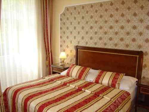 a bedroom with a bed with a red and yellow blanket at Hotel Saint Petersburg in Karlovy Vary