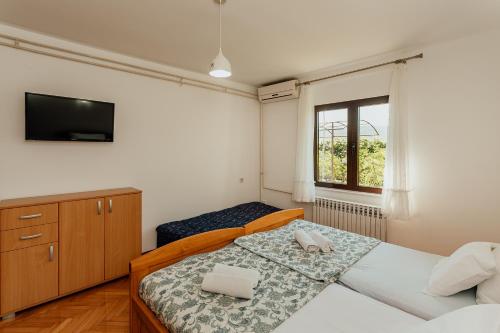 a bedroom with two beds and a flat screen tv at Apartmani Jasna in Herceg-Novi