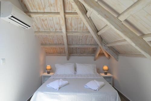 una camera da letto con un letto con lenzuola bianche e due lampade di FAMILY a Spetses