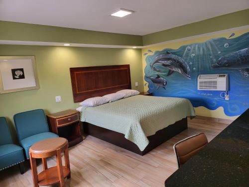 - une chambre avec un lit orné d'une peinture murale dans l'établissement Travel Inn of Riviera Beach, à Riviera Beach