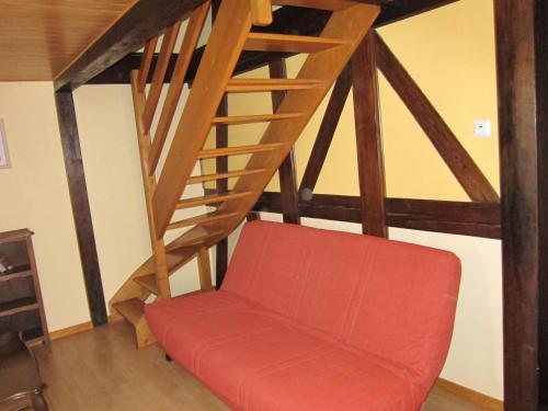 a red chair in a room with a staircase at Gîte la Ferme in Mutzig
