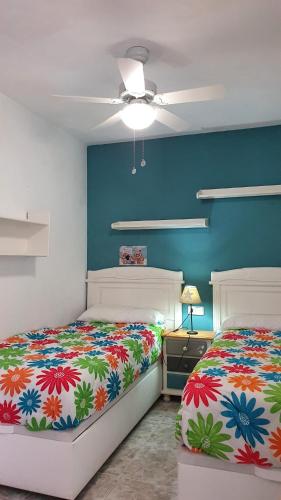 a bedroom with two beds and a ceiling fan at Urbanova Apartment in El Alted