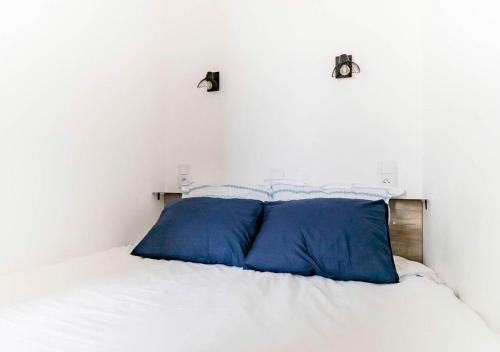 Una cama blanca con dos almohadas azules. en Les Bords de l'Estaque x Studio Braque en Marsella