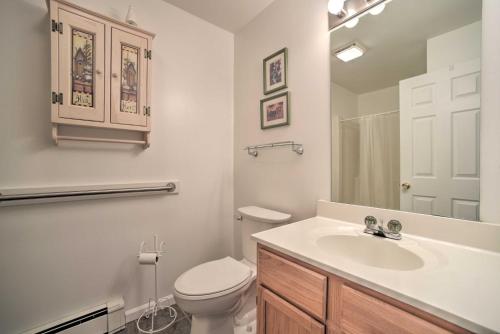 a white bathroom with a toilet and a sink at Bolton Landing Suite with Deck, Lake George Access in Bolton Landing