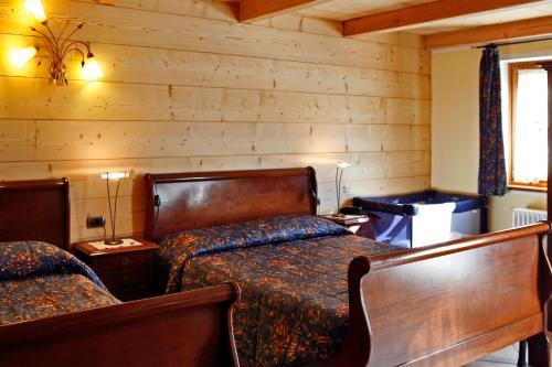 a bedroom with two beds in a room with wooden walls at Les Combes in La Salle