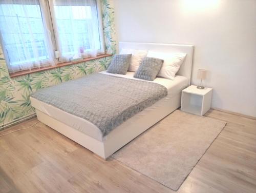 a white bed in a room with two windows at Stardust apartman in Pécs