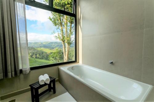 baño con bañera y ventana grande en Pousada Casa Bambu, en Cunha