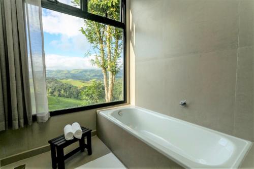 a bathroom with a tub and a large window at Pousada Casa Bambu in Cunha