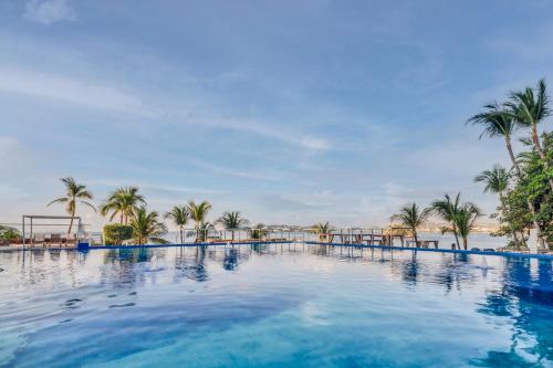 a large swimming pool with palm trees and the ocean at Fiesta Americana Acapulco Villas in Acapulco