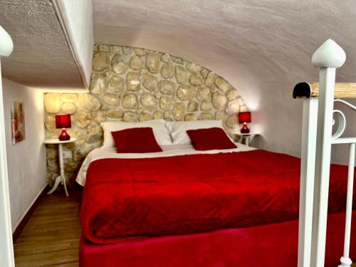a bedroom with a red bed with a stone wall at Le Chalet Palermo Centro in Palermo