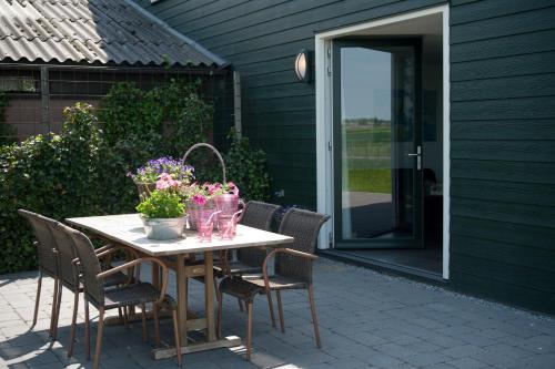 a table with chairs and flowers on a patio at Newhouse Logies in Zevenhoven