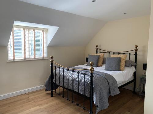een slaapkamer met een zwart bed met kussens en een raam bij Kellsboro Corner in Fairford