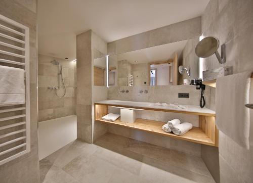 a bathroom with a shower and a sink and a mirror at Familienhotel Post in Serfaus