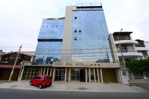 un coche rojo estacionado frente a un edificio alto en Hotel Lucky Star en Chiclayo